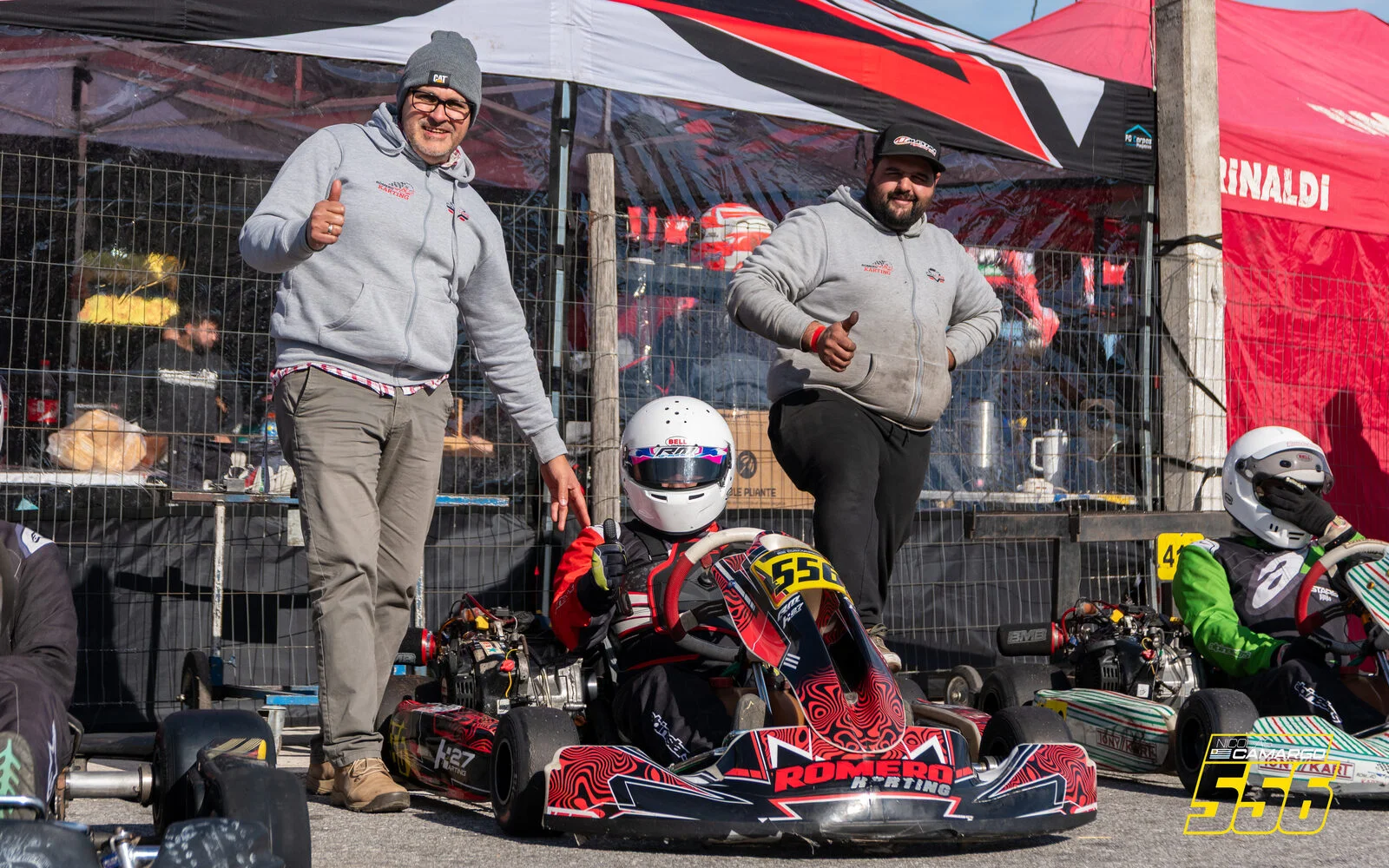 Nicolás Camargo sentado en su kart 556 de Karting 27 en el paddock de San José, con dos integrantes de su equipo a los costados