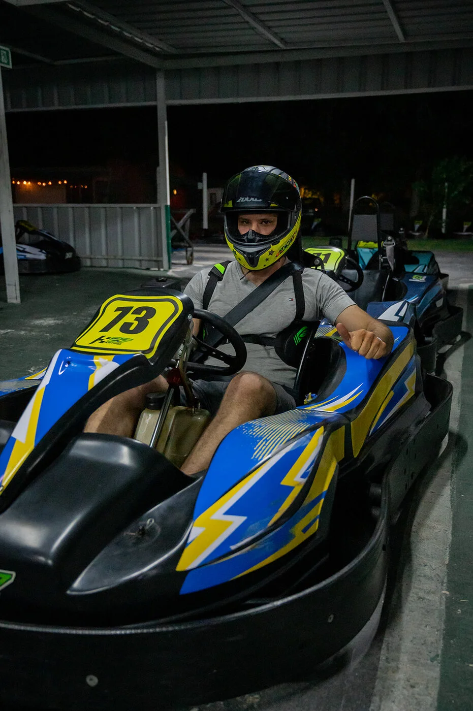 Piloto con el pulgar arriba listo para largar de noche en Karting 27